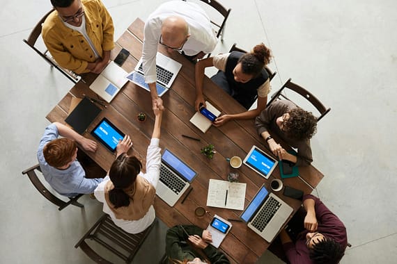 pexels-photo-3183197-3183197-1 Top view of a diverse team collaborating in an office setting with laptops and tablets, promoting cooperation.